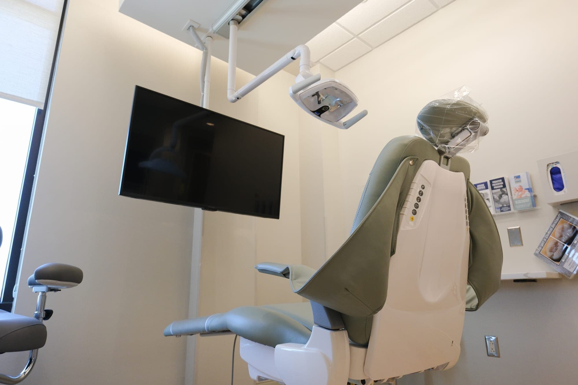 A treatment room at Camenzuli Dental Excellence, with the chair, overhead light and ceiling-mounted screen