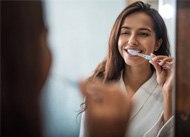 a person smiling while brushing their teeth