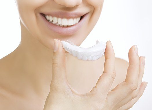 Woman using at-home teeth whitening kit