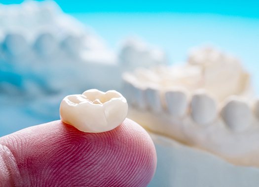 A closeup of a dental crown on a person’s finger