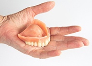 Hand holding dentures on white background