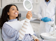 Patient smiling at reflection in handheld mirror