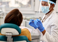 Smiling dentist talking to patient in treatment room