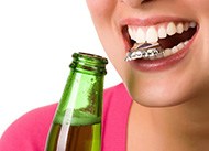 Woman holding bottle cap between her teeth