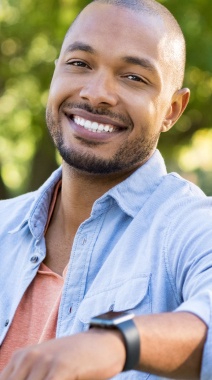 Smiling man outdoors wearing light blue shirt