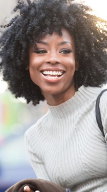 Woman in white sweater smiling outdoors