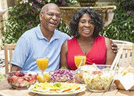 couple sitting at a table outside with food and drinks 