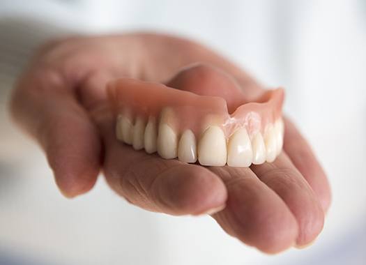 Hand holding a full denture