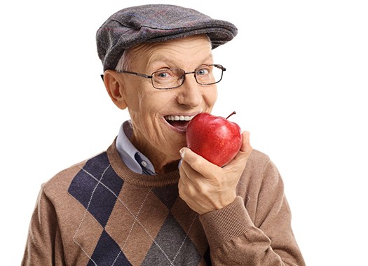 An older man biting into an apple.