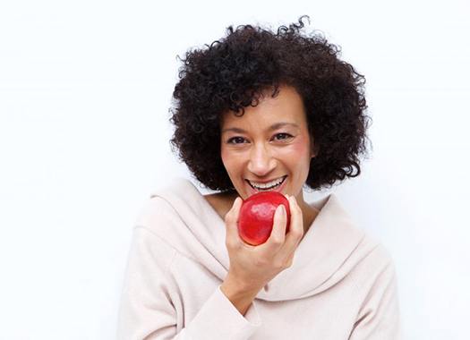 older woman biting into red apple 
