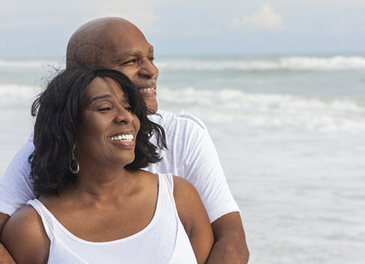 An older couple smiling on a beach.