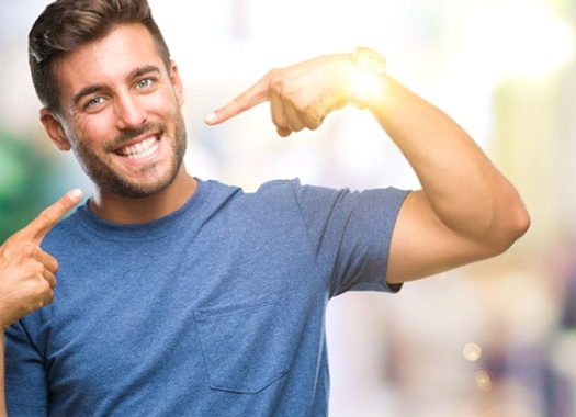 man pointing to his smile with veneers in Uptown New Orleans