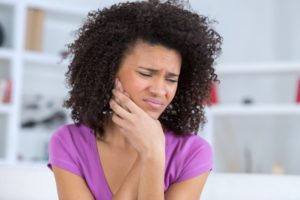 girl in purple shirt holding face in pain