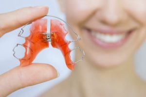 Closeup of orange retainer held by woman in background