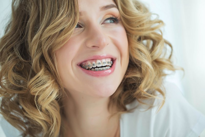 an up-close image of a young woman with blonde hair smiling and showing off her metal braces