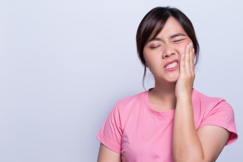 patient suffering from facial pain holding cheek