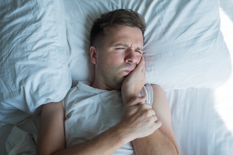 A man suffering from a toothache at night